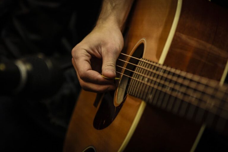 homem tocando as cordas de um violão
